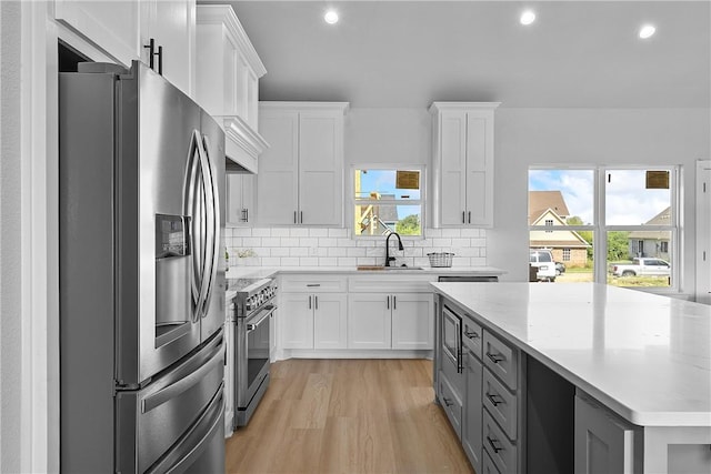 kitchen with backsplash, light stone counters, white cabinetry, and stainless steel appliances