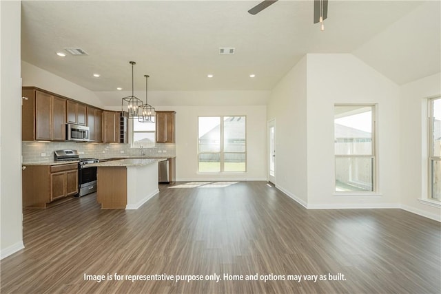 kitchen with appliances with stainless steel finishes, dark wood-type flooring, a center island, hanging light fixtures, and lofted ceiling