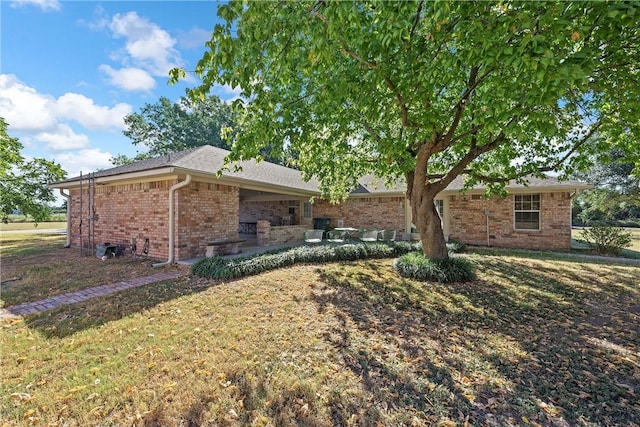 view of side of property with brick siding, a lawn, and a patio