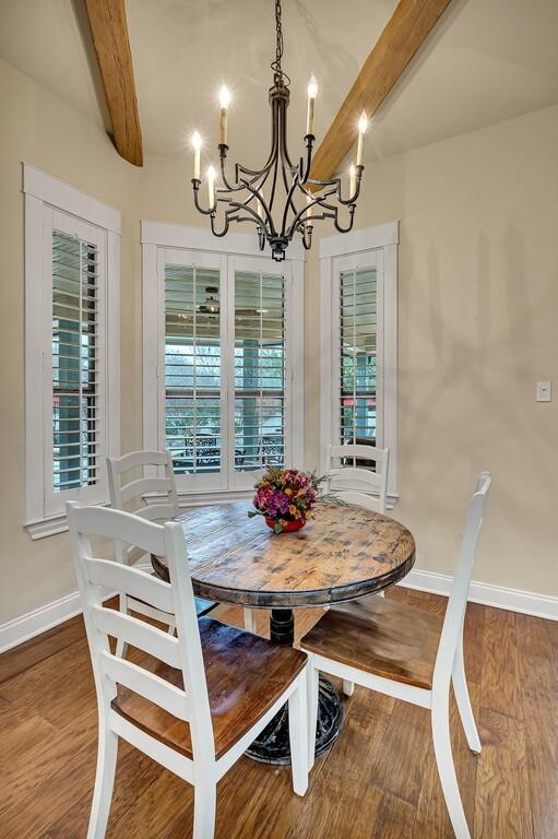 dining room with beamed ceiling, a notable chandelier, and wood-type flooring