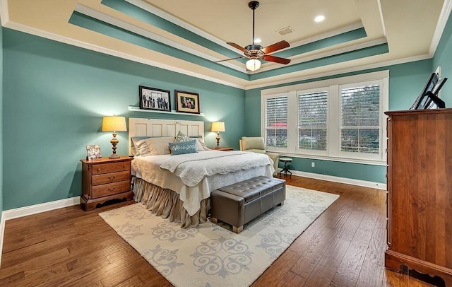 bedroom with a raised ceiling, ceiling fan, dark wood-type flooring, and ornamental molding