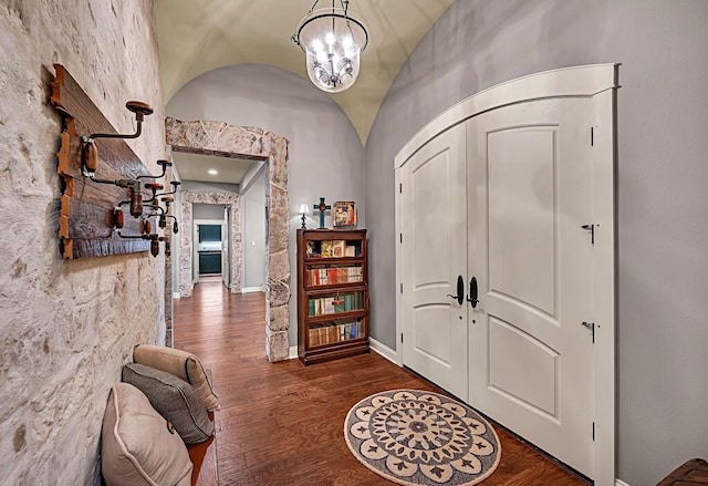 entrance foyer featuring vaulted ceiling, dark hardwood / wood-style flooring, and a chandelier