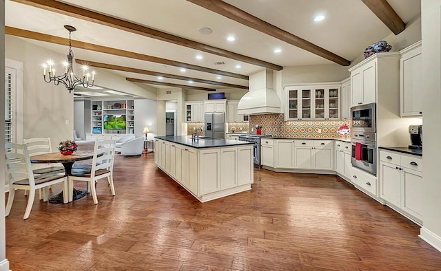 kitchen with beam ceiling, decorative light fixtures, appliances with stainless steel finishes, custom exhaust hood, and hardwood / wood-style flooring