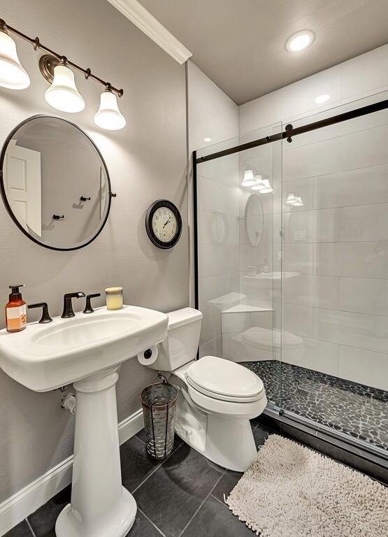 bathroom with tile patterned flooring, toilet, walk in shower, and crown molding