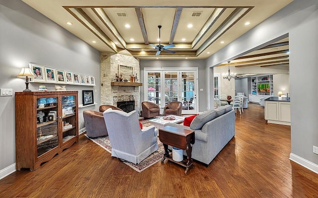 living room featuring a fireplace, beam ceiling, ceiling fan with notable chandelier, and dark wood-type flooring