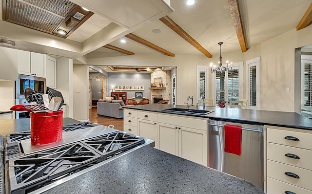 kitchen featuring appliances with stainless steel finishes, sink, beam ceiling, white cabinetry, and hanging light fixtures