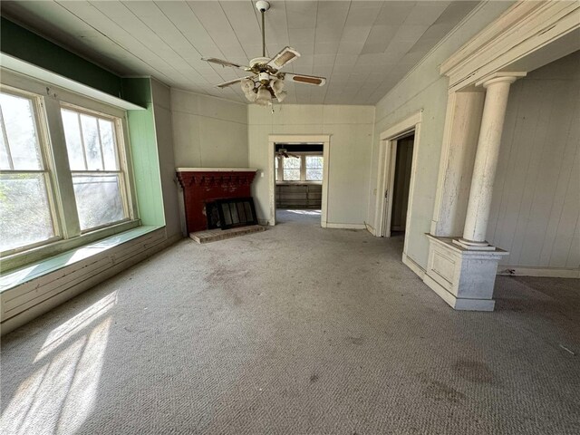 unfurnished living room with ornate columns, ceiling fan, and light colored carpet