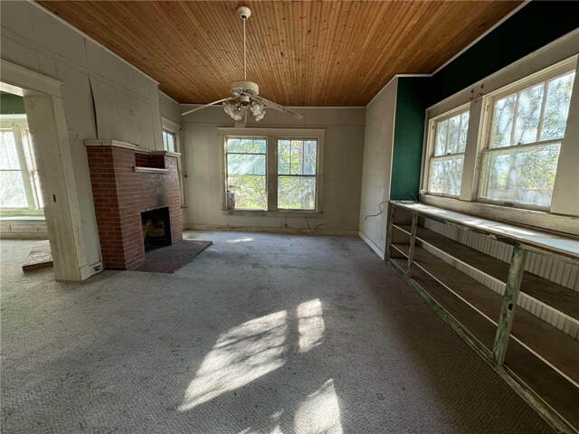 unfurnished living room with wood ceiling, ceiling fan, light colored carpet, and a brick fireplace