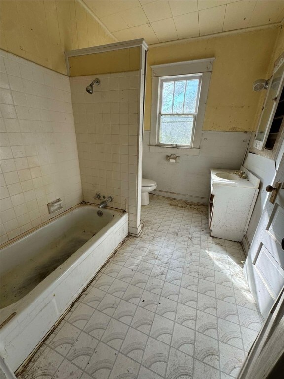 bathroom with tiled shower / bath combo and toilet