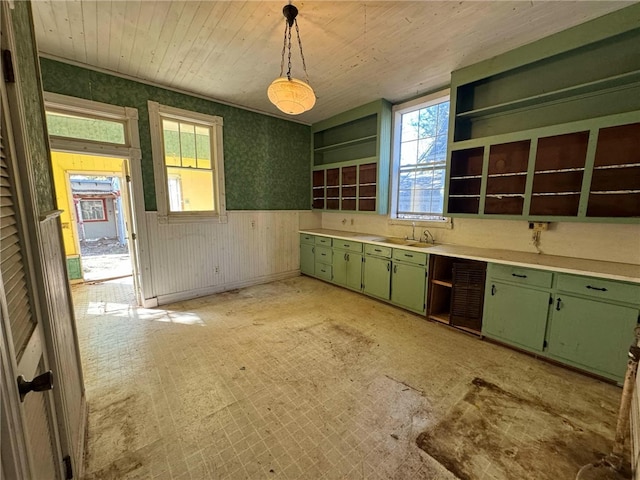 kitchen with sink, hanging light fixtures, wooden walls, and green cabinetry