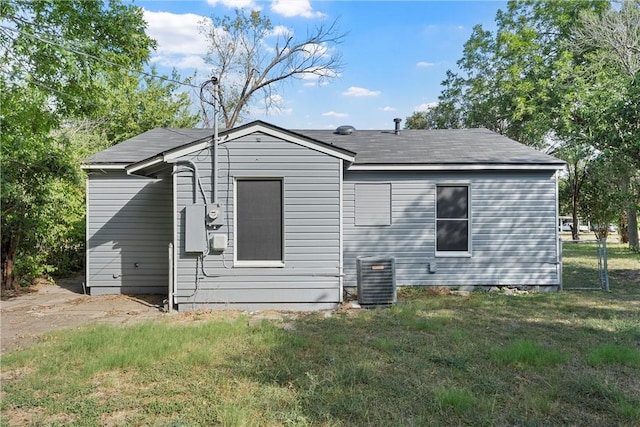 rear view of house featuring central air condition unit and a yard