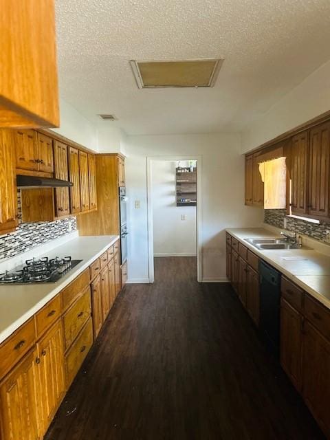 kitchen featuring sink, dishwasher, dark wood-type flooring, stainless steel gas cooktop, and decorative backsplash