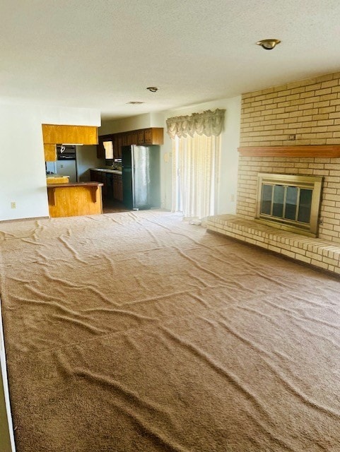 unfurnished living room featuring a fireplace, carpet, and a textured ceiling