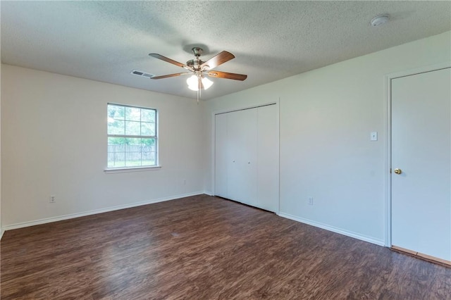 unfurnished bedroom featuring a textured ceiling, dark hardwood / wood-style flooring, a closet, and ceiling fan