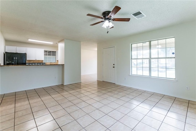 unfurnished living room with ceiling fan, light tile patterned flooring, and a textured ceiling