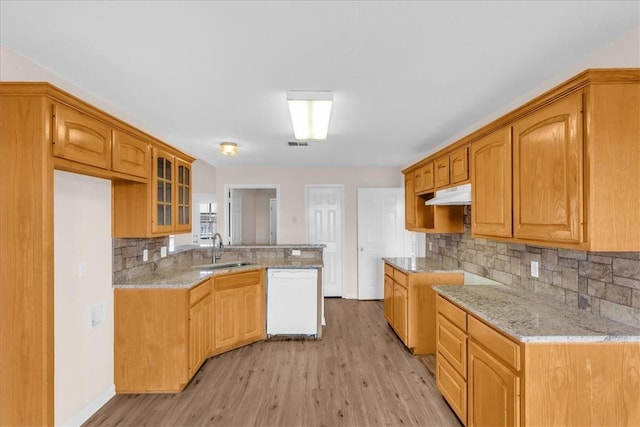 kitchen featuring light stone countertops, sink, tasteful backsplash, white dishwasher, and light hardwood / wood-style floors