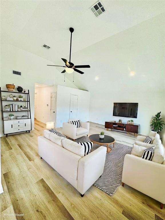 living room with light wood-type flooring, high vaulted ceiling, and ceiling fan