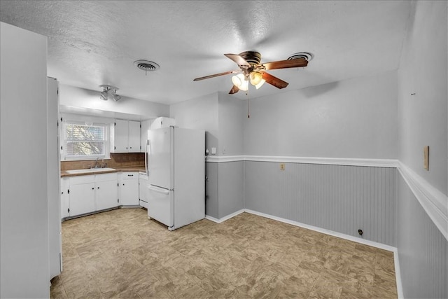 kitchen featuring a textured ceiling, ceiling fan, sink, white cabinets, and white fridge