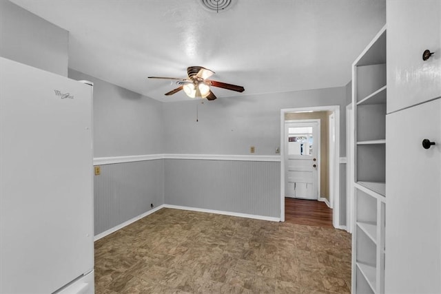 unfurnished room with ceiling fan and wooden walls