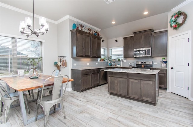 kitchen featuring dark brown cabinetry, hanging light fixtures, crown molding, and stainless steel appliances