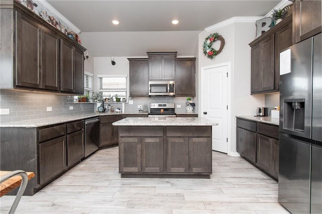 kitchen featuring dark brown cabinetry, stainless steel appliances, a center island, and light stone countertops