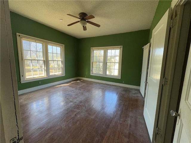 empty room with a healthy amount of sunlight, ceiling fan, hardwood / wood-style flooring, and a textured ceiling