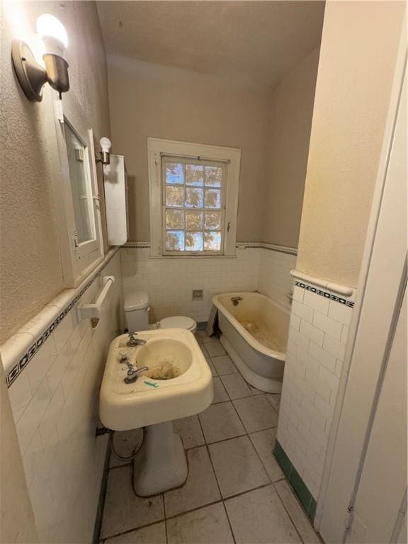 bathroom featuring tile walls, tile patterned floors, a bathtub, and toilet