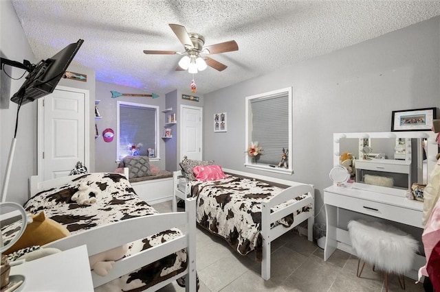 bedroom featuring a textured ceiling, ceiling fan, and light tile patterned flooring