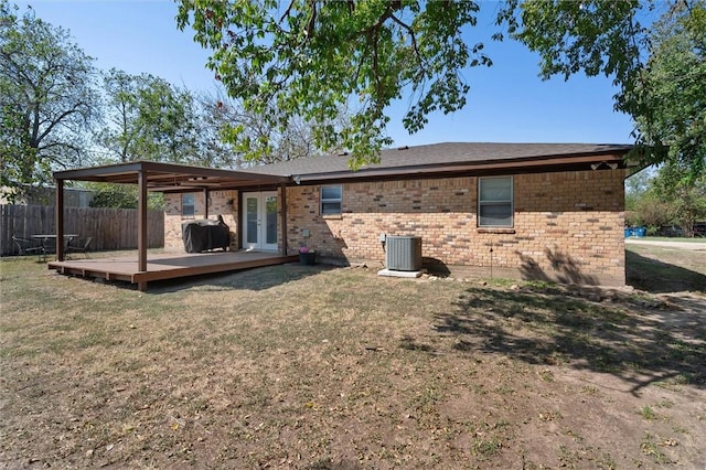 back of property featuring central AC unit, a wooden deck, and a lawn