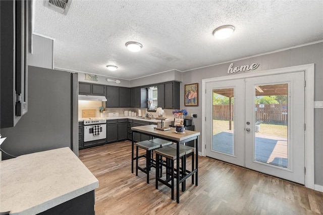 kitchen featuring light wood-type flooring, french doors, electric range, and a textured ceiling