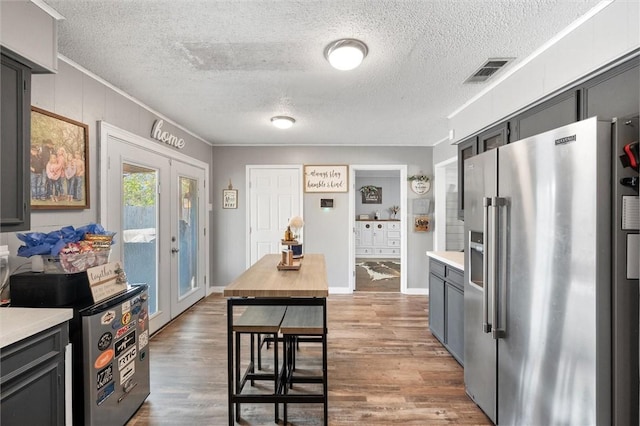 kitchen with hardwood / wood-style floors, french doors, high end refrigerator, crown molding, and a textured ceiling