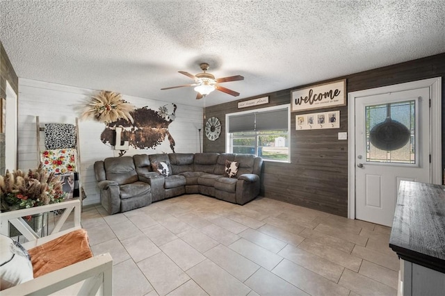 living room featuring a textured ceiling, ceiling fan, and wooden walls