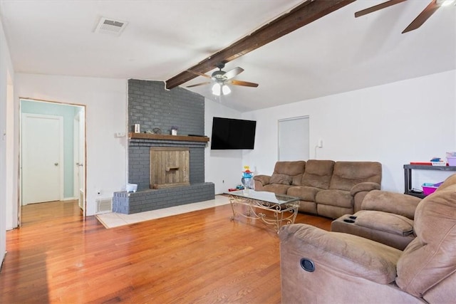 living room featuring lofted ceiling with beams, ceiling fan, wood-type flooring, and a brick fireplace