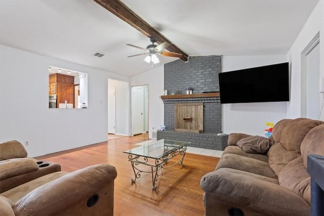 living room featuring ceiling fan, a fireplace, lofted ceiling with beams, and light hardwood / wood-style floors