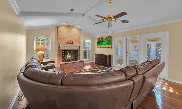 living room featuring wood finished floors, baseboards, lofted ceiling with beams, crown molding, and a brick fireplace