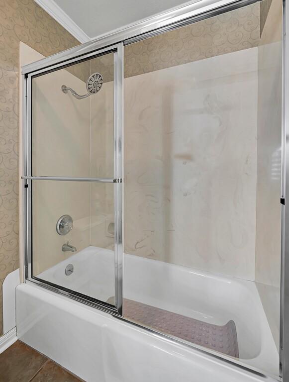 full bath featuring enclosed tub / shower combo, tile patterned floors, wallpapered walls, and crown molding