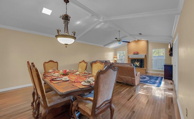 dining area with lofted ceiling with beams, baseboards, wood finished floors, and a fireplace