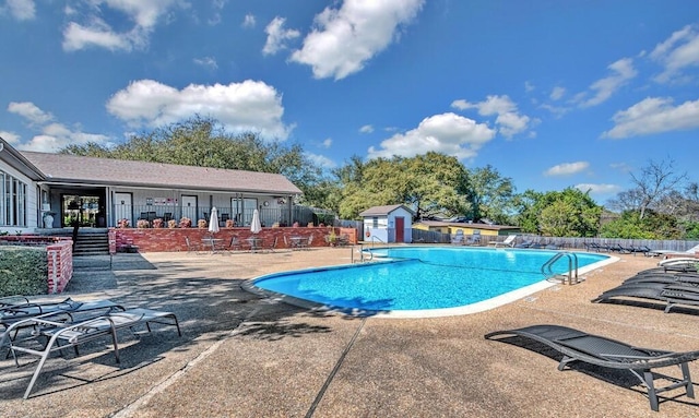 pool with a patio area, an outdoor structure, and fence