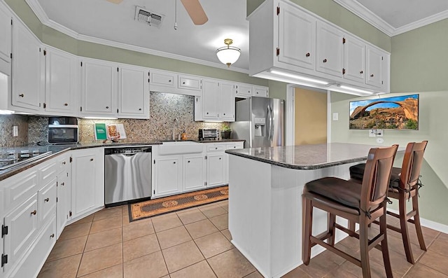 kitchen featuring visible vents, a sink, white cabinetry, appliances with stainless steel finishes, and crown molding