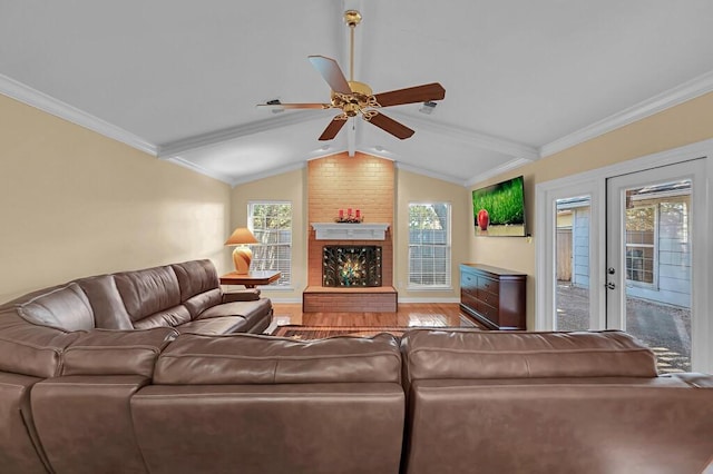 living room featuring a ceiling fan, wood finished floors, vaulted ceiling with beams, a fireplace, and ornamental molding