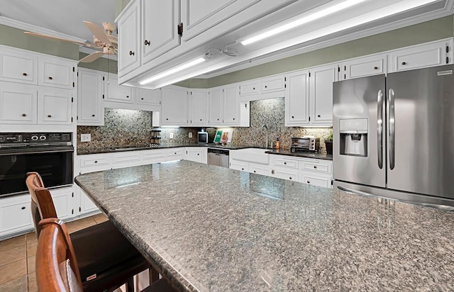 kitchen with tasteful backsplash, black appliances, crown molding, and a sink