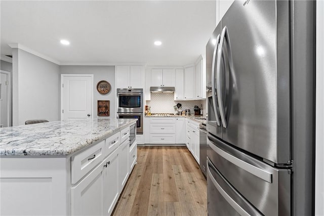 kitchen with under cabinet range hood, white cabinetry, appliances with stainless steel finishes, and a center island