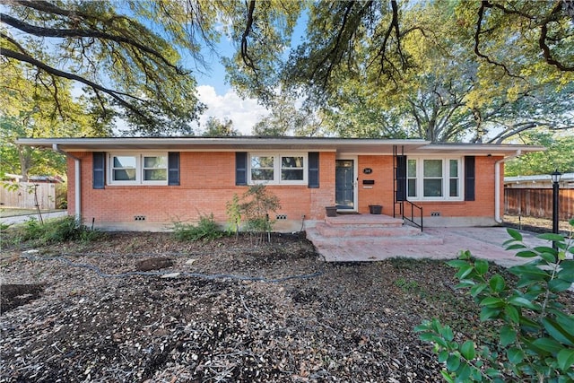 ranch-style home featuring brick siding and fence