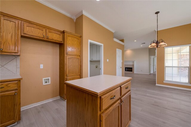 kitchen with pendant lighting, a center island, an inviting chandelier, light wood-type flooring, and ornamental molding