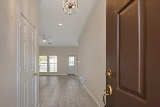 entrance foyer featuring light hardwood / wood-style flooring, ceiling fan with notable chandelier, and ornamental molding