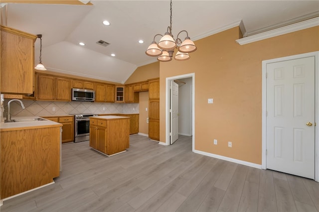 kitchen featuring a center island, sink, ornamental molding, appliances with stainless steel finishes, and decorative light fixtures