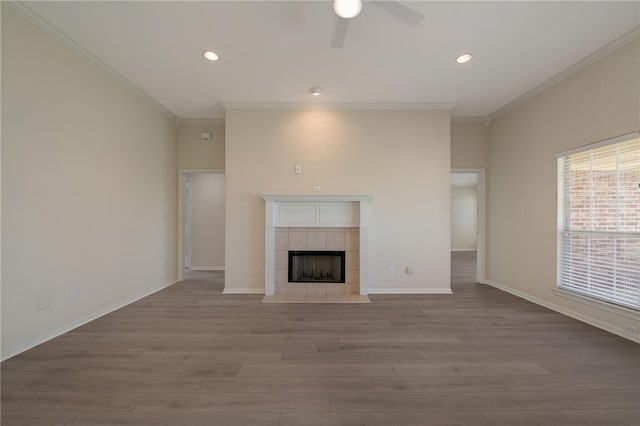 unfurnished living room with a tile fireplace, ornamental molding, and light wood-type flooring