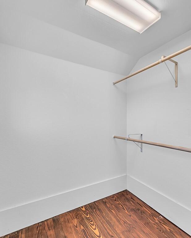 walk in closet featuring vaulted ceiling and dark hardwood / wood-style floors