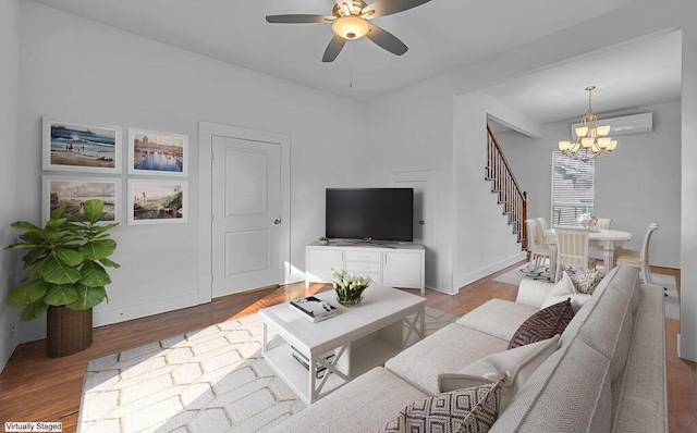 living room featuring a wall mounted air conditioner, ceiling fan with notable chandelier, and light hardwood / wood-style flooring