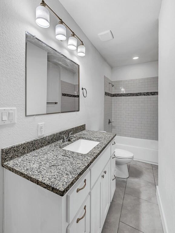 full bathroom with tile patterned floors, vanity, toilet, and tiled shower / bath